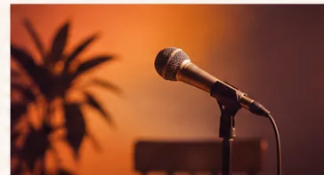 Microfone sobre palco iluminado em tons de laranja